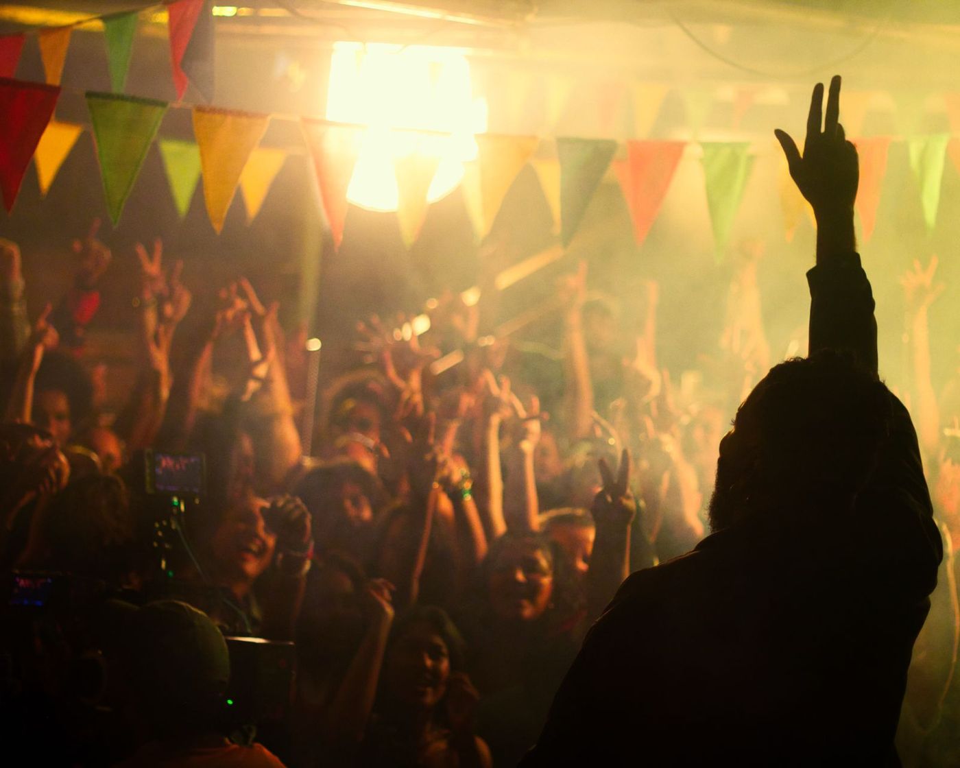 Raised hand silhouetted against bunting and warm haze