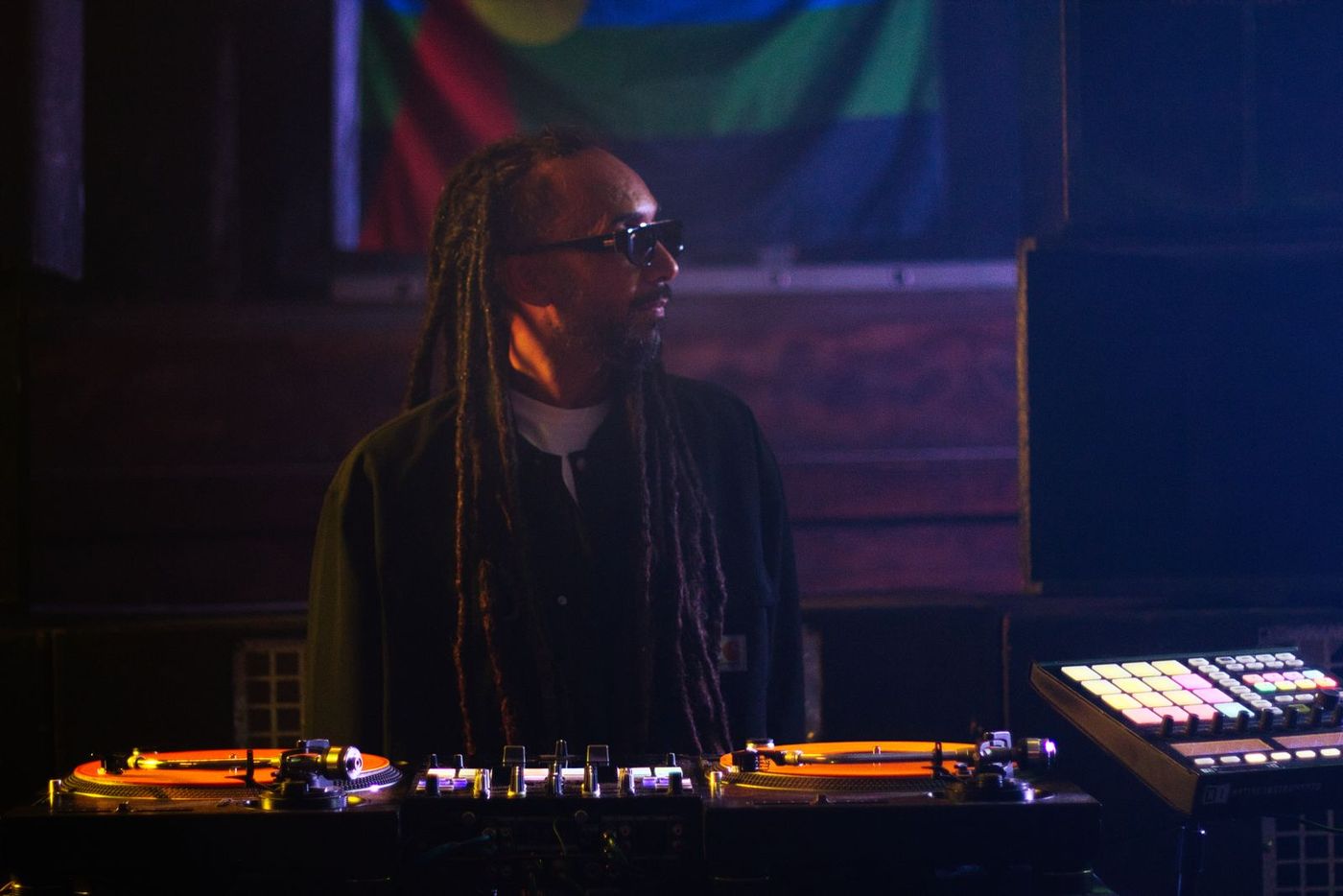 DJ with long locks behind turntables and a mixer