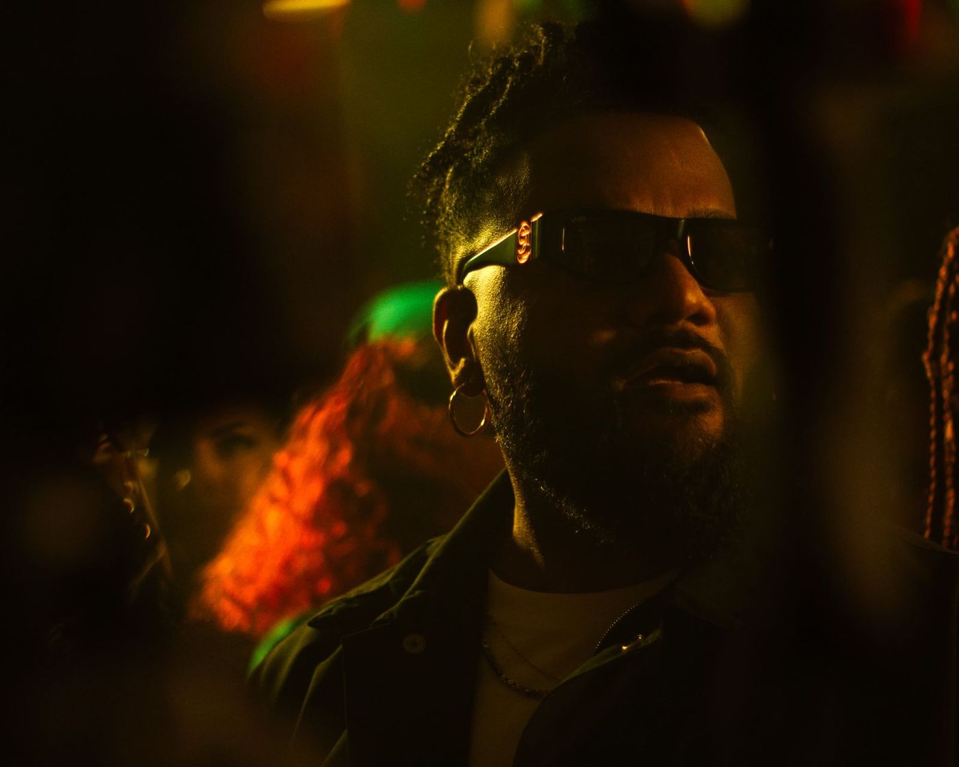 Man in sunglasses lit by green and orange light