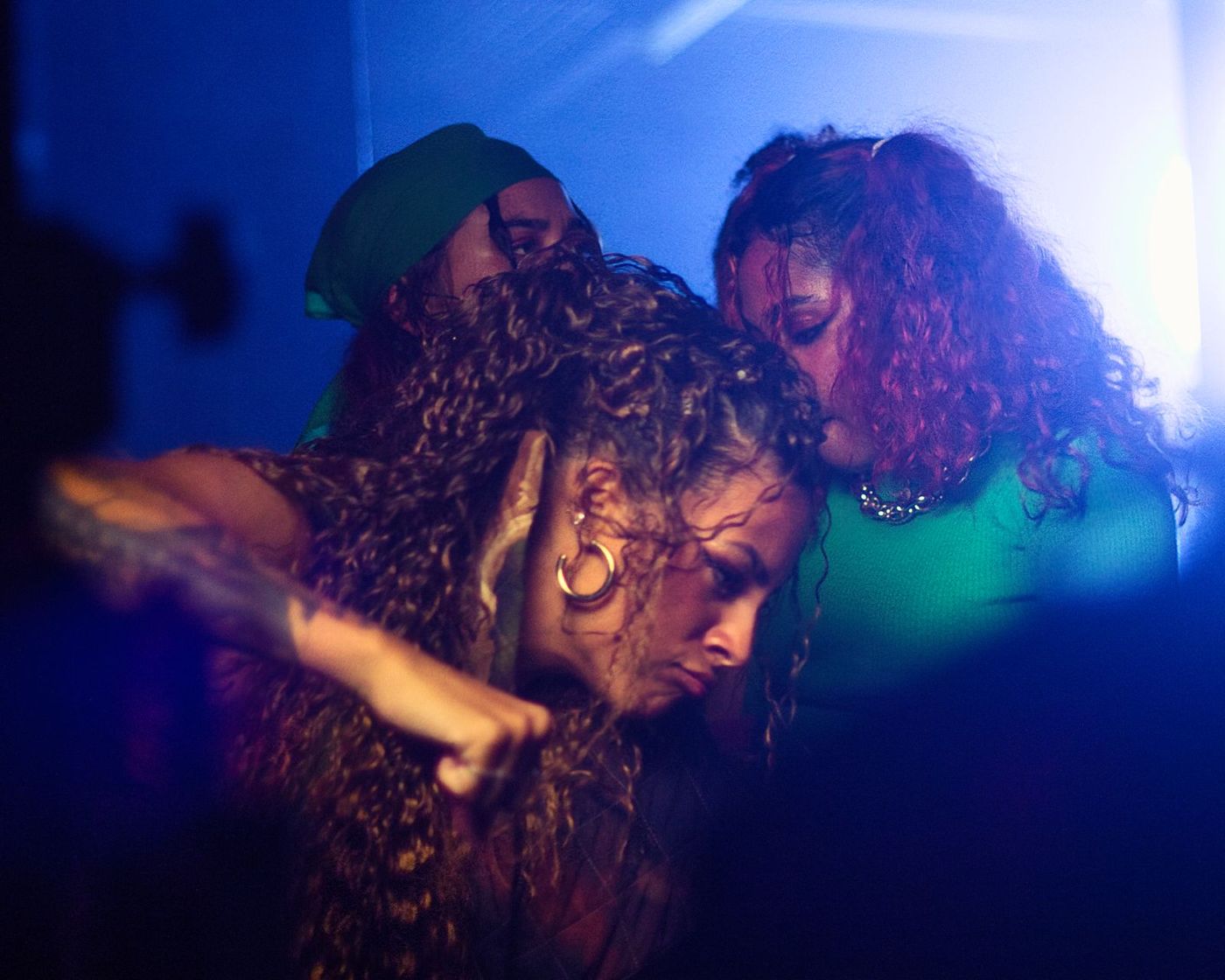 Two women dancing close in blue light