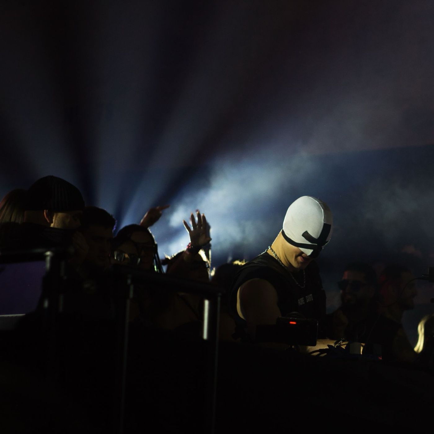 Masked performer in haze and beams of light