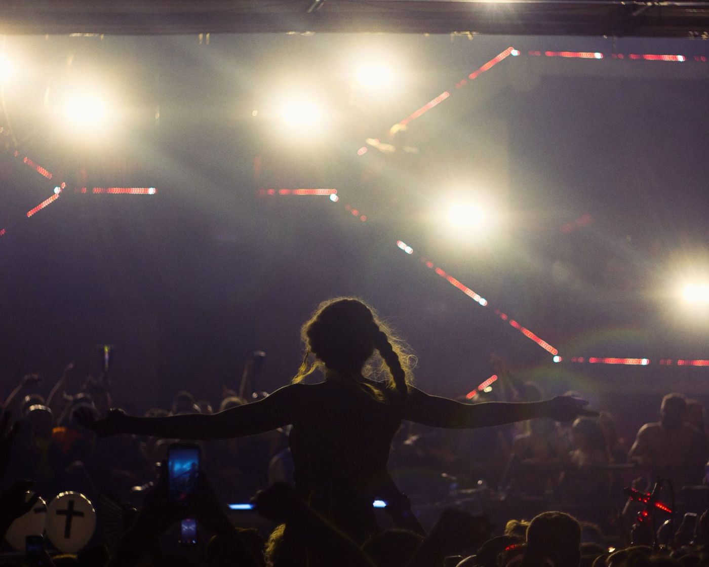 Woman with arms wide in front of stage lights