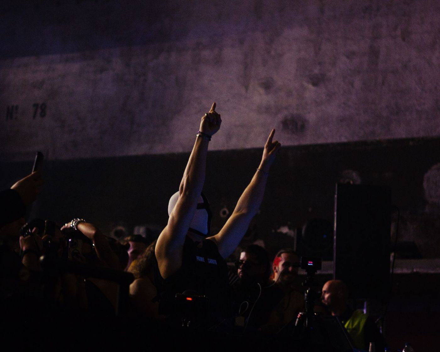 Hands raised in the crowd under a concrete ceiling