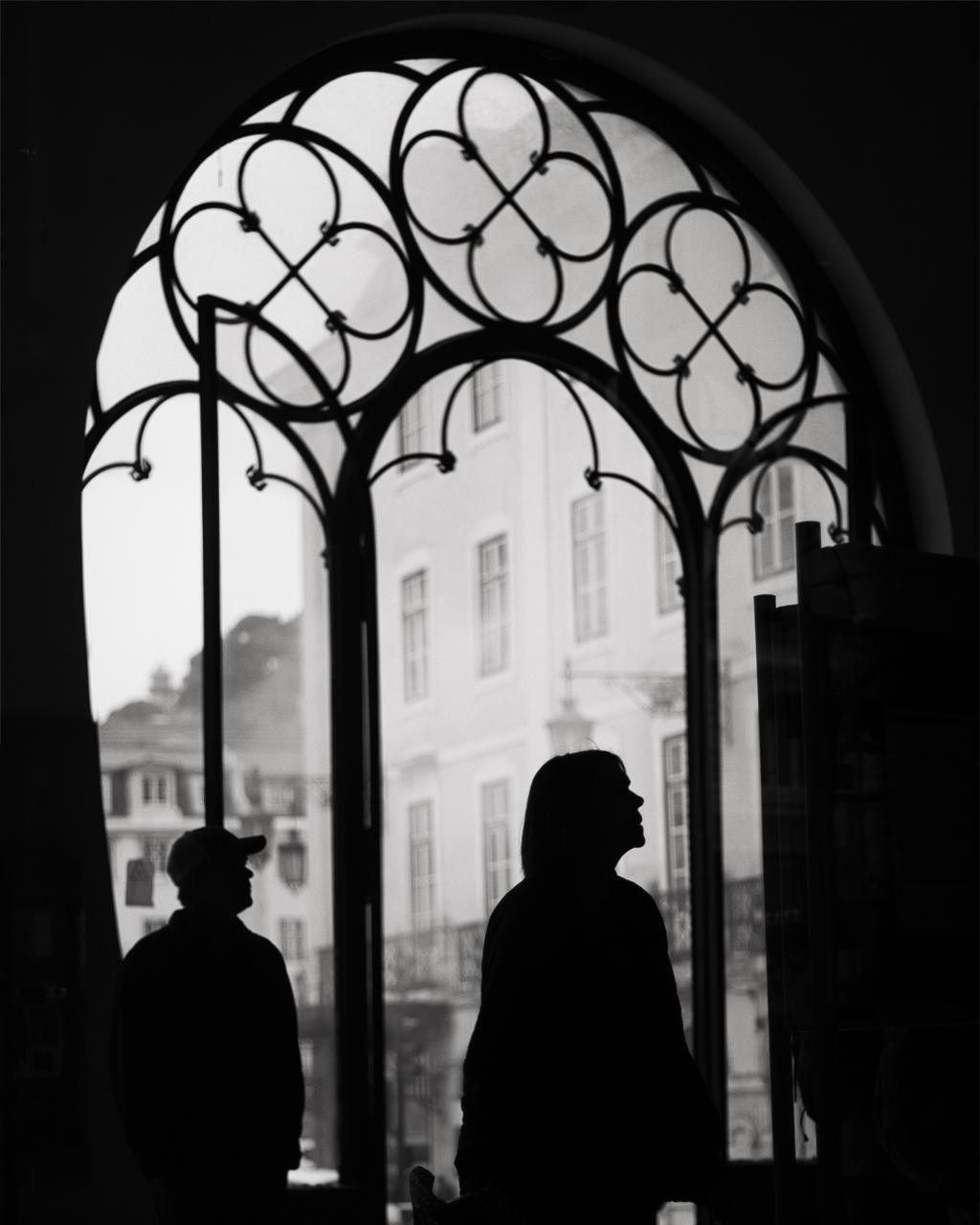 Silhouettes in an ornate arched window over Lisbon