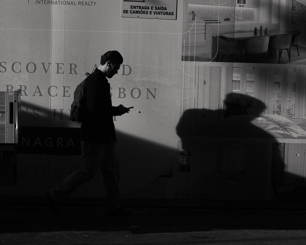 Man walking past a wall with long shadows