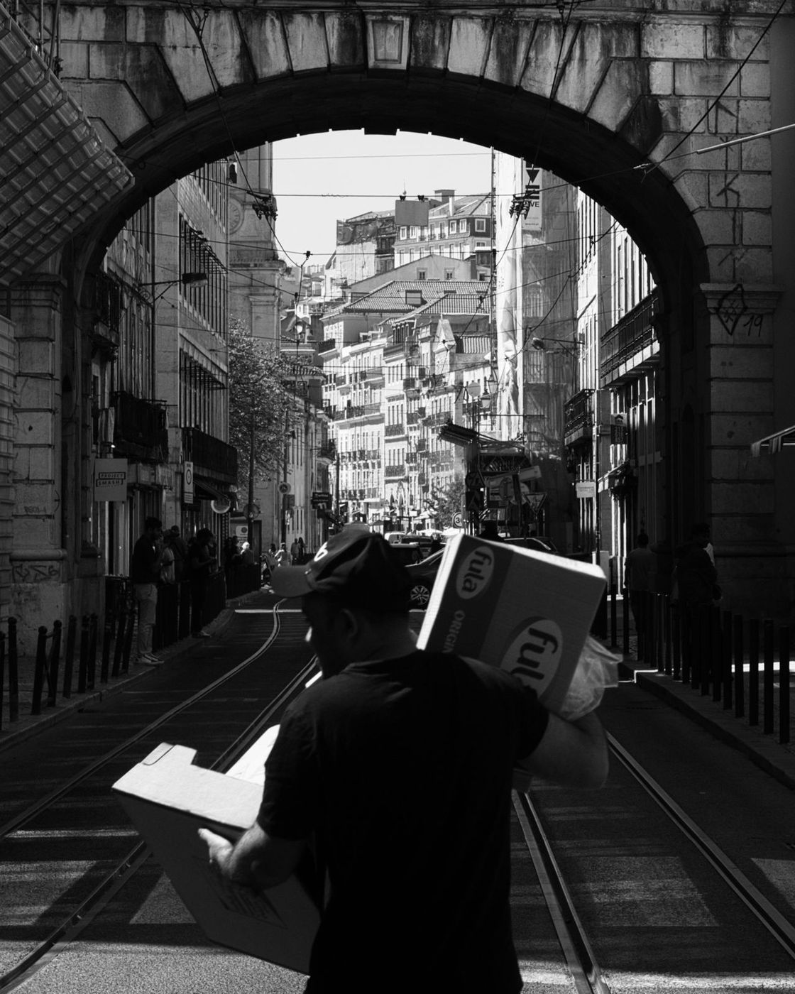 Courier under a stone arch with tram tracks