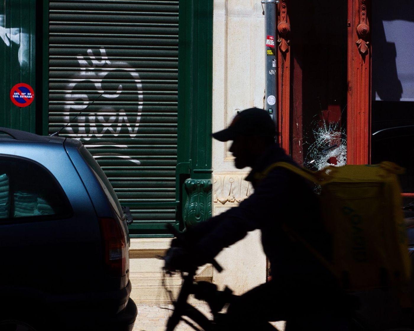 Courier on a bike silhouetted against a green shutter