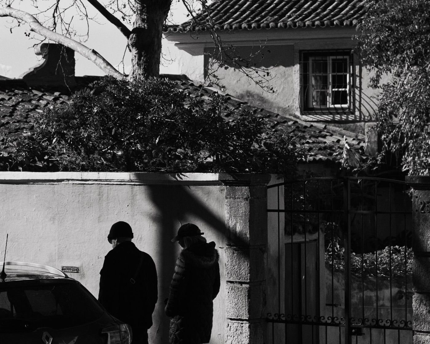 Two silhouettes under a shaded garden wall