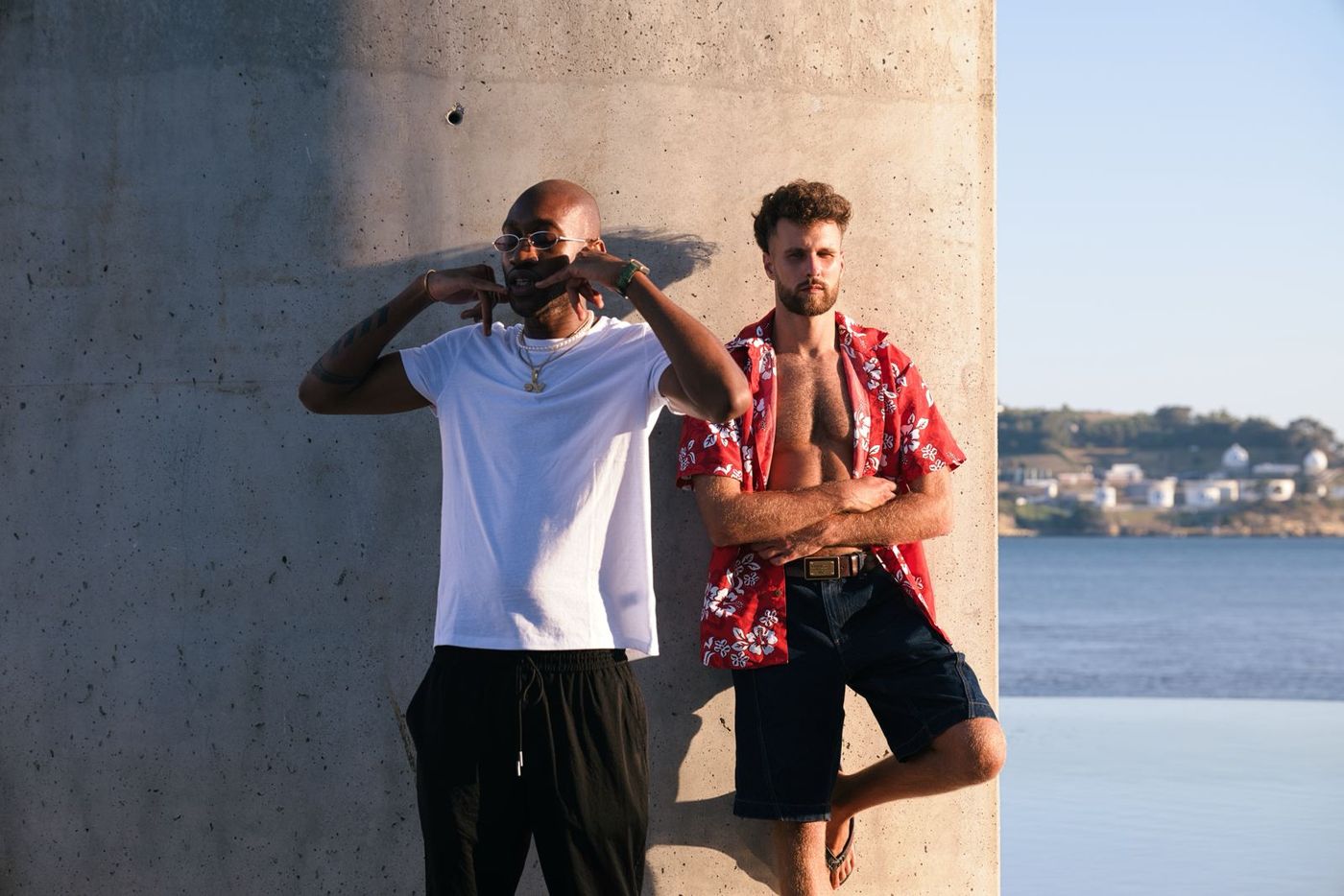 Two men against a concrete pillar by the river