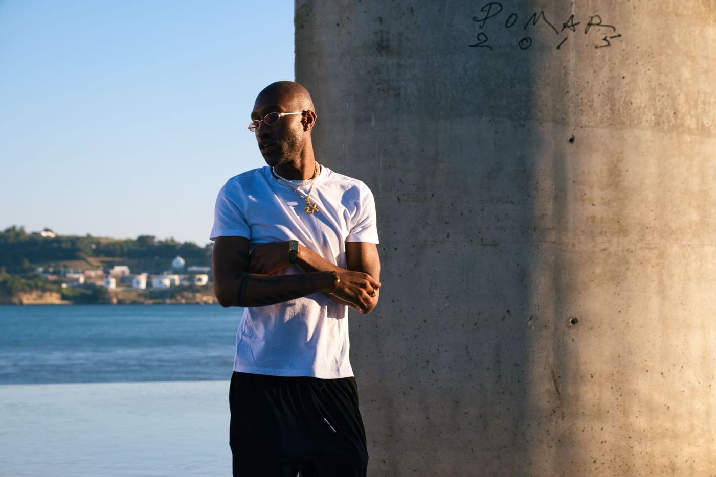 Man with arms crossed beside a pillar by the water