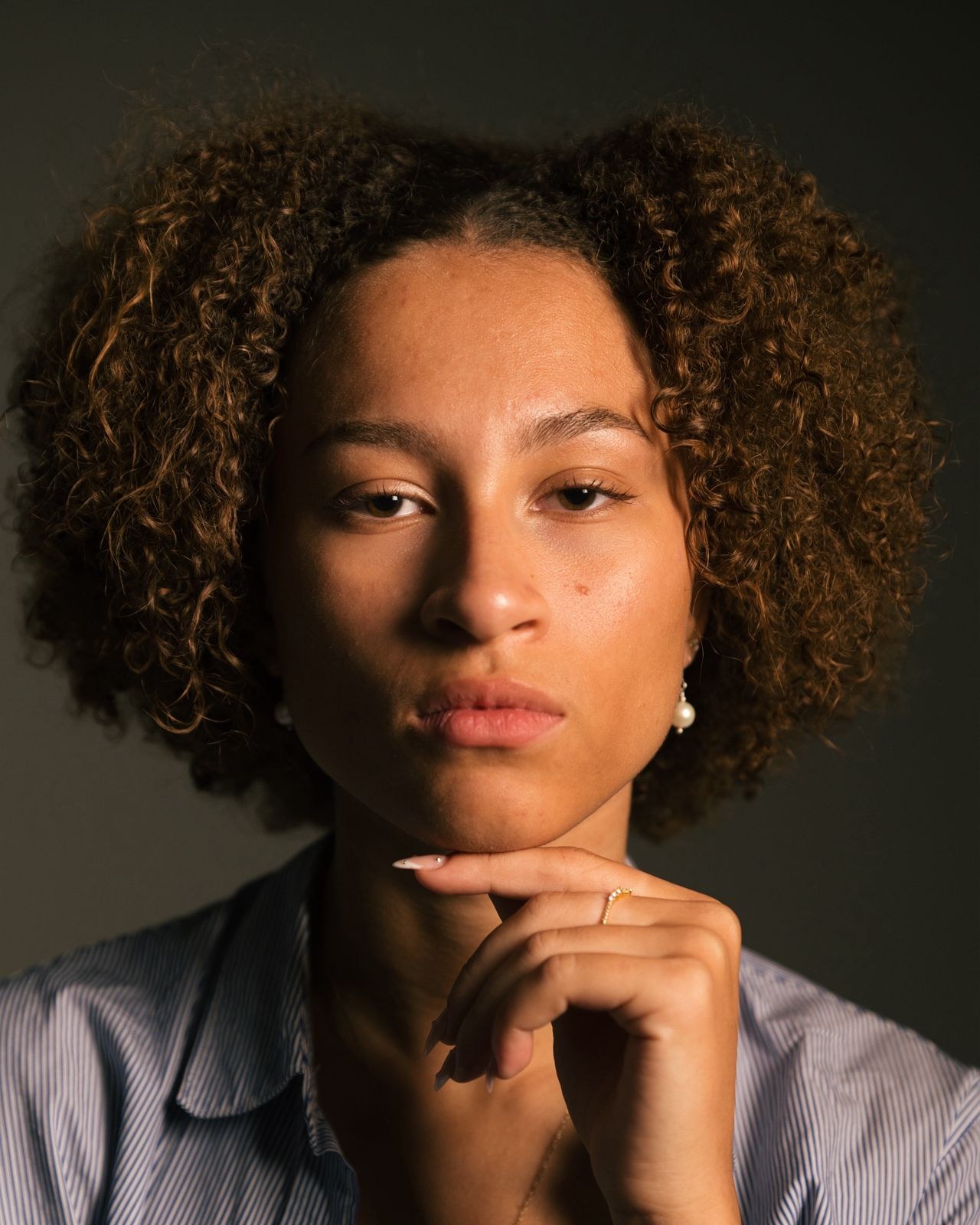 Close portrait of a woman with caramel curls and a pearl earring