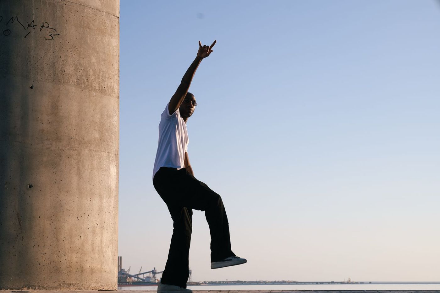 Silhouette of a man reaching up beside a concrete pillar